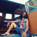 smiling young hippie man in minivan car